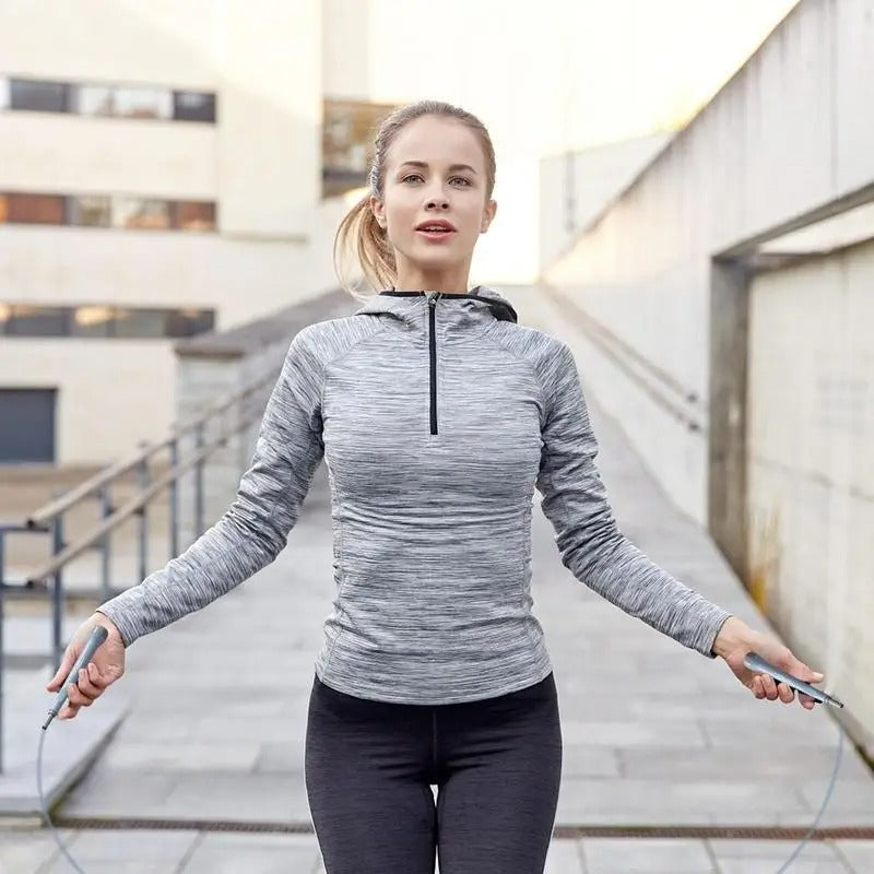 Femme face en tenue de sport gris, noir qui saute à la corde