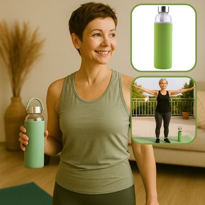 Femme mature debout sur sa terrasse après une séance de sport doux, en train de boire dans sa gourde verte – retour au calme et fraîcheur

